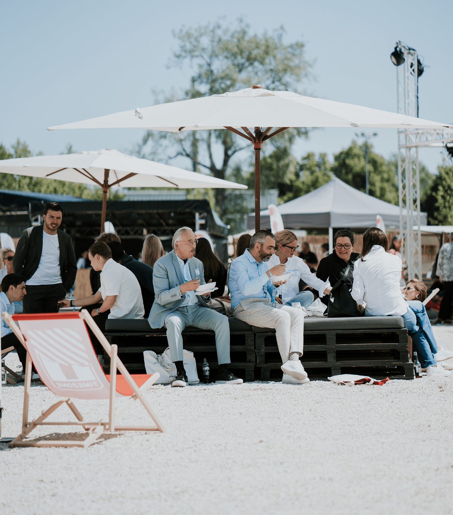 Besucher sitzen und unterhalten sich im sonnigen Außenbereich des unitex-FashionFestival 2024